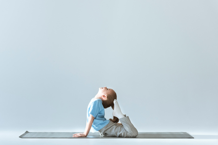 Side view of sporty girl practicing King Pigeon Posture on matの写真素材