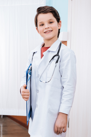 boy doctor with stethoscope holding clipboard and smiling at cameraの写真素材