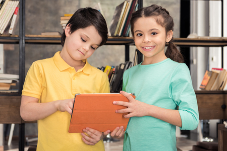 smiling schoolchildren using digital tablet togetherの写真素材