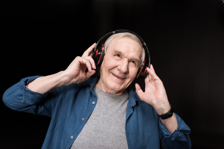 happy senior man listening music in headphones on blackの写真素材