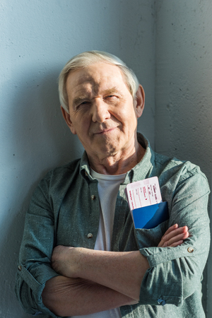 smiling senior man with passports and tickets in pocket, traveling conceptの写真素材