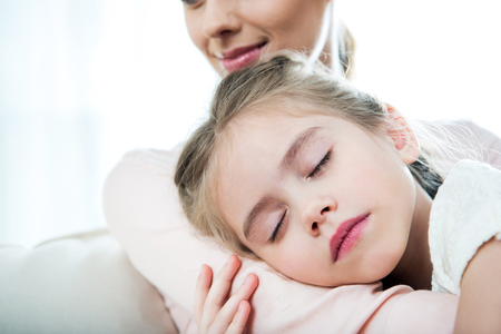girl sleeping on mothers arm at homeの写真素材