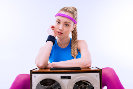 woman in fitness clothing sitting near retro record playerの写真素材