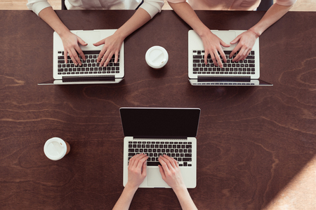 businesswomen typing on laptops at tableの写真素材