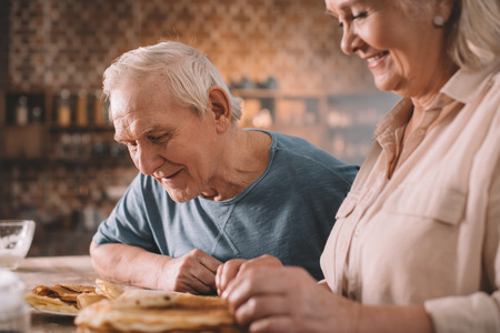 couple eating pancakes on kitchen at homeの写真素材
