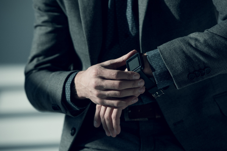 Close-up partial view of man in stylish suit using smartwatchの写真素材