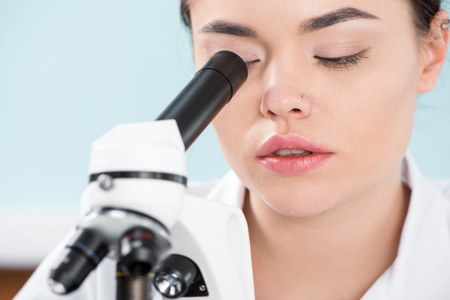 Woman looking in microscopeの写真素材