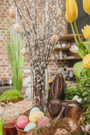 Beautiful Easter composition of catkins, colorful eggs, fresh flowers and chocolate rabbitの写真素材