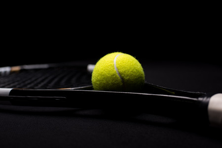 Close-up view of tennis ball and racquet  on blackの写真素材