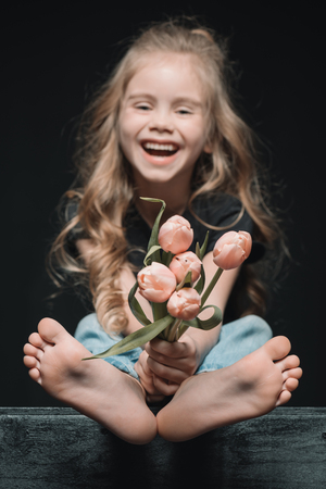laughing girl holding tulips bouquet on blackの写真素材