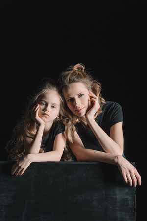pensive stylish daughter and mother looking at cameraの写真素材