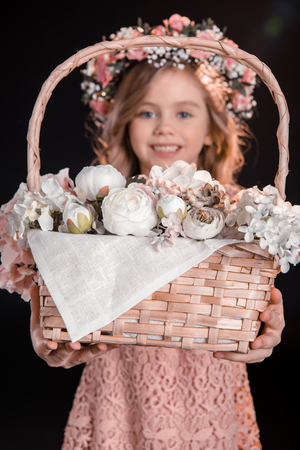 smiling girl in floral wreath showing beautiful flower basketの写真素材