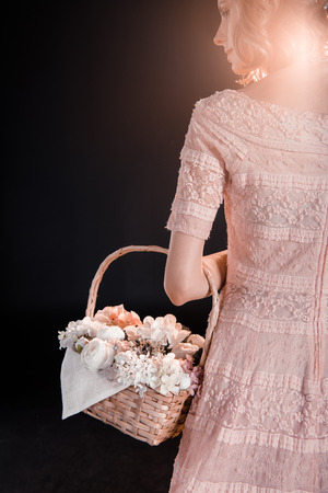 young woman in pink dress walking with flower basketの写真素材