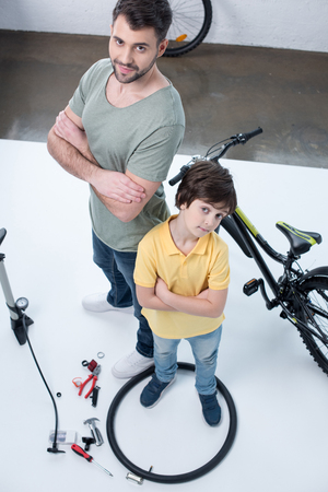 father and son standing near bicycle on whiteの写真素材