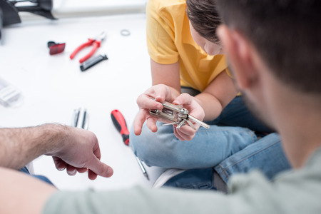 father teaching son to use bicycle multi tool on white