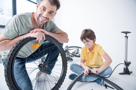 Son and father repairing bicycle tire in studioの写真素材