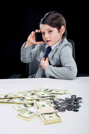 portrait of confident boy playing businessman and talking on smartphoneの写真素材