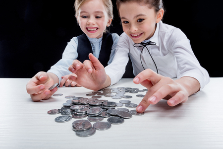 portrait of little girls sitting at table and calculating moneyの写真素材