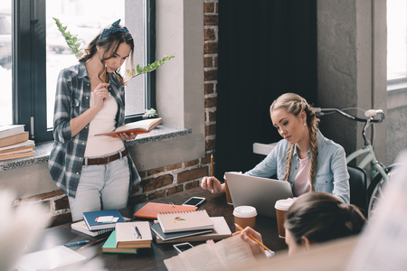 girls students drinking coffee and studying together at deskの写真素材
