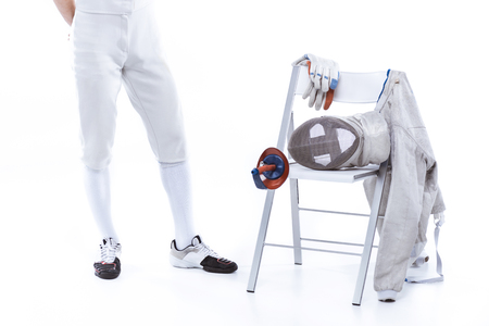 young man professional fencer standing near chair with fencing equipmentの写真素材