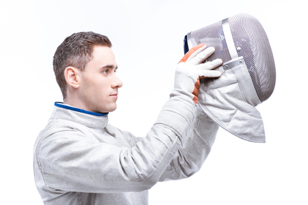 young man professional fencer wearing helmet on white