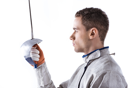 young man professional fencer holding rapier on white