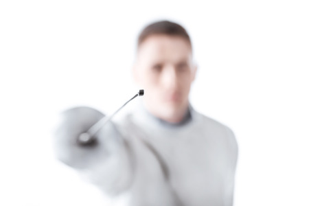 young man professional fencer holding rapier on whiteの写真素材