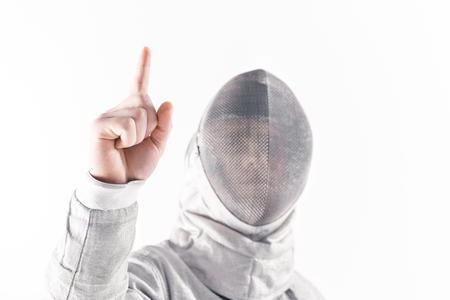 Portrait of professional fencer in fencing mask pointing upの写真素材