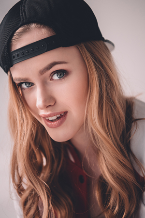 smiling young woman in cap looking at cameraの写真素材