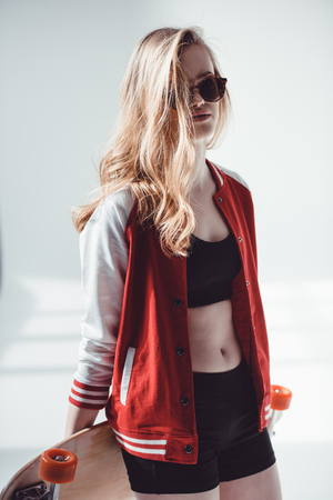 Stylish hipster woman with longboard posing in studioの写真素材