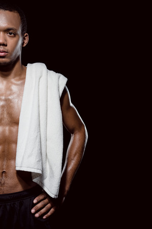 african sporty man with towel on shoulder on blackの写真素材