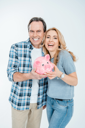 Front view of happy couple holding piggy bankの写真素材