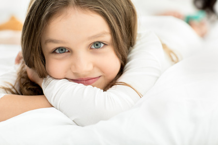 little adorable girl lying and relaxing on bed at homeの写真素材