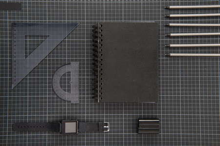Flat lay of black office supplies, notepad, smartwatch and pencils