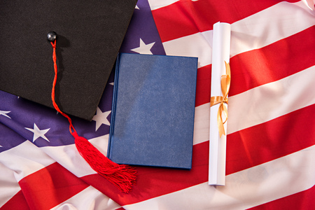 Top view of book, graduation cap and diploma on american flagの写真素材