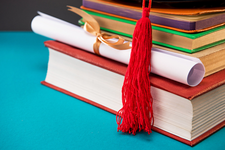 close up of books, diploma and graduation cap with tassel on blueの写真素材