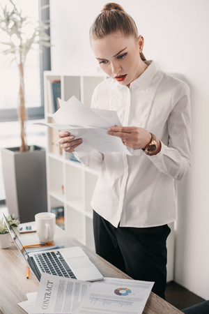 concentrated businesswoman reading contract documents in officeの写真素材