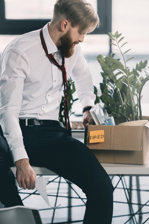 upset fired businessman with cardboard box in officeの写真素材