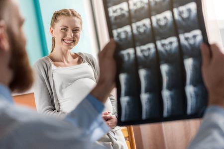 pregnant woman looking at doctor holding mri scanの写真素材