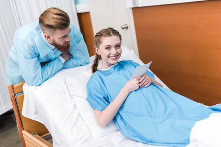 pregnant woman and man holding sonogram in hospitalの写真素材
