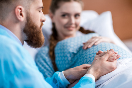 pregnant smiling woman with husband holding handsの写真素材