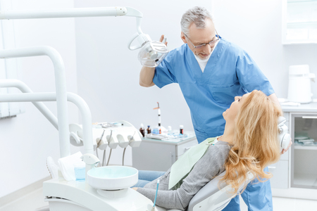 dentist in uniform talking with patient in dental clinicの写真素材