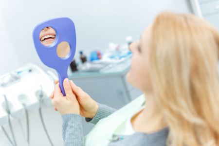 beautiful blonde woman with mirror at dental check upの写真素材