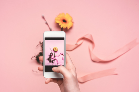 cropped view of person taking photo of flower with ribbon on smartphone. springtime conceptの写真素材