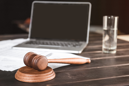 brown wooden judge hammer and documents with laptop behind, law conceptの写真素材
