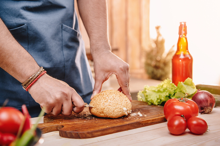 man making burgers and cutting red tomatoesの写真素材