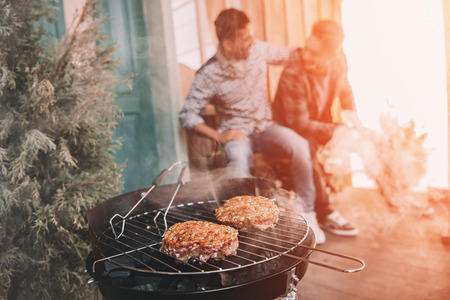 young friends making barbecue on porch with back lightの写真素材