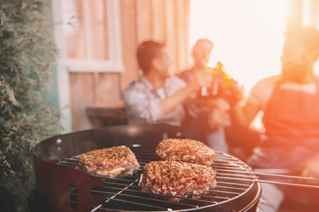 young friends making barbecue on porch with back lightの写真素材
