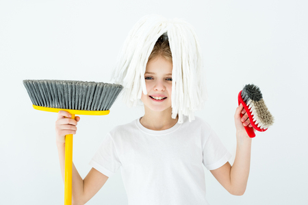 smiling little girl holding various cleaning supplies on whiteの写真素材