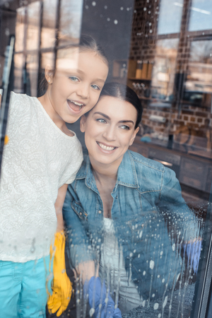 mother and cute little daughter cleaning window togetherの写真素材
